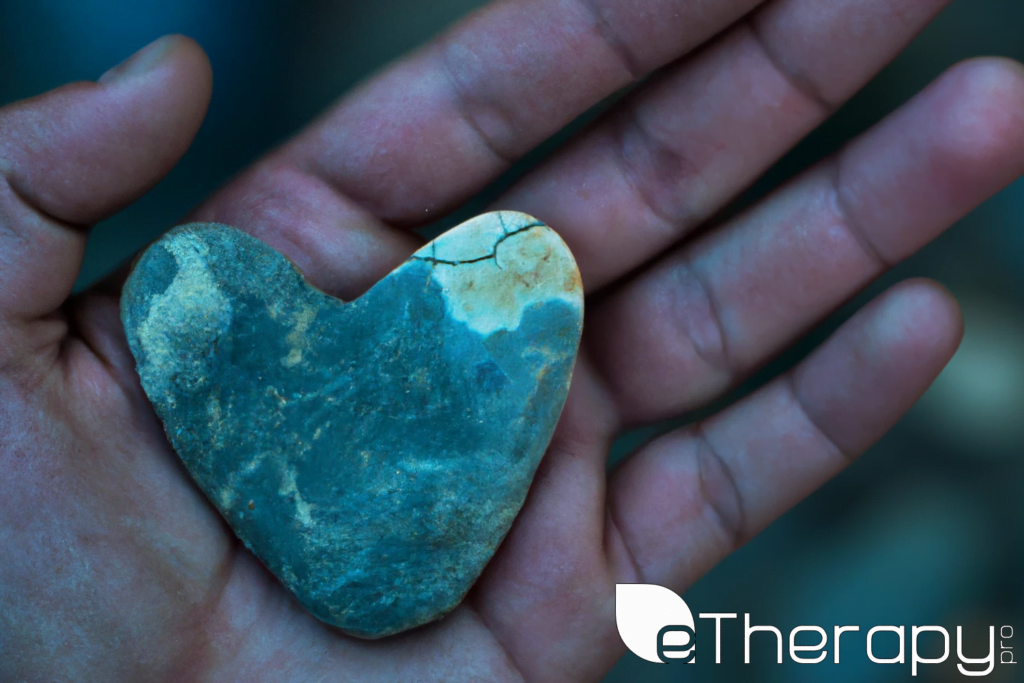 person's hand gently holding a stone shape of a heart - How Can I Develop Self Compassion